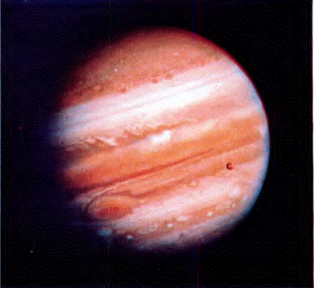 Voyager I uzay sondasının 1979'da çektiği bu fotoğrafta, Jüpiter gezegeninin çevresinin renkli bulut kuşaklarıyla çevrili olduğu görülmektedir. Resmin orta sağında görülen nokta, İo uydusudur. İo'nun yüzeyinde yanardağ etkinlikleri olduğu anlaşılmıştır.